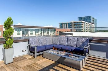 A blue couch with a white patterned cushion is on a wooden deck.